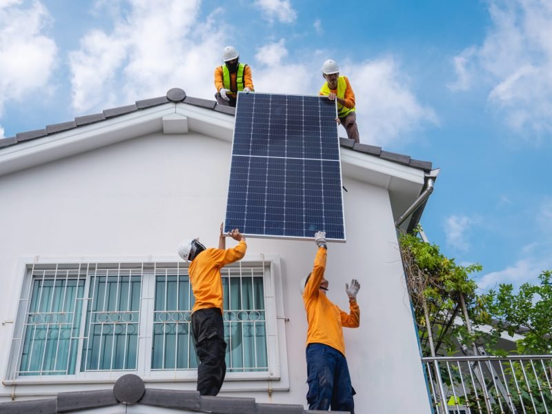 Service engineer installing solar cell on the roof of house. Technicians working about solar panel system outdoors. Clean and Renewable energy concept.