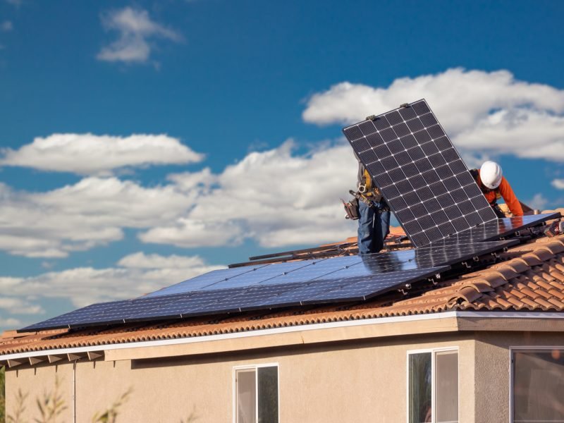 Workers Installing Solar Panels on House Roof.