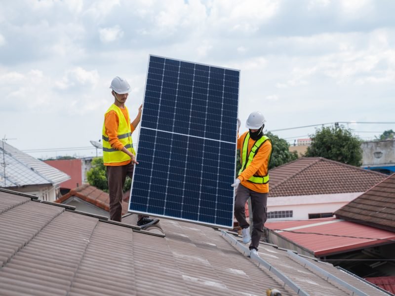 Service engineer installing solar cell on the roof of house. Technicians working about solar panel system outdoors. Clean and Renewable energy concept.